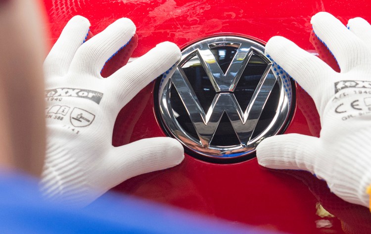 A worker checks the Volkswagen emblem on a Golf car in Zwickau, Germany. <em>Associated Press/Jens Meyer</em>