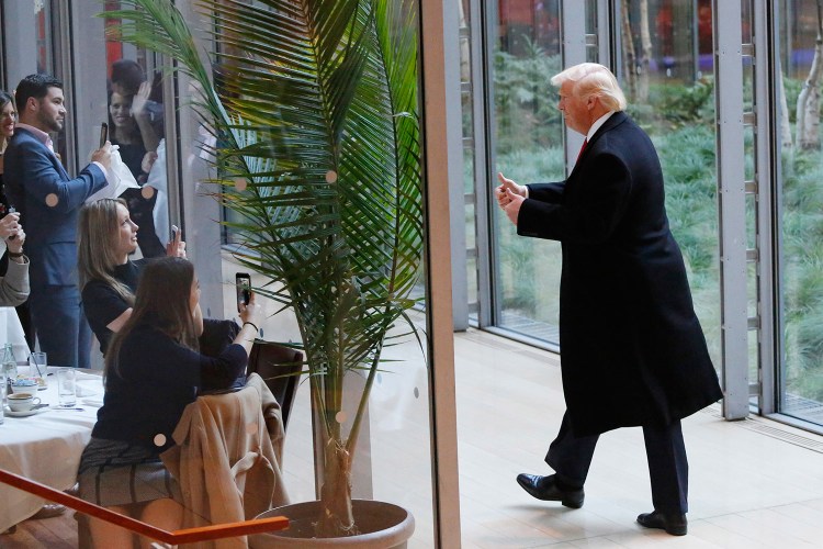 President-elect Donald Trump gestures to people seated in a restaurant as he leaves the New York Times building following a meeting Tuesday in New York.