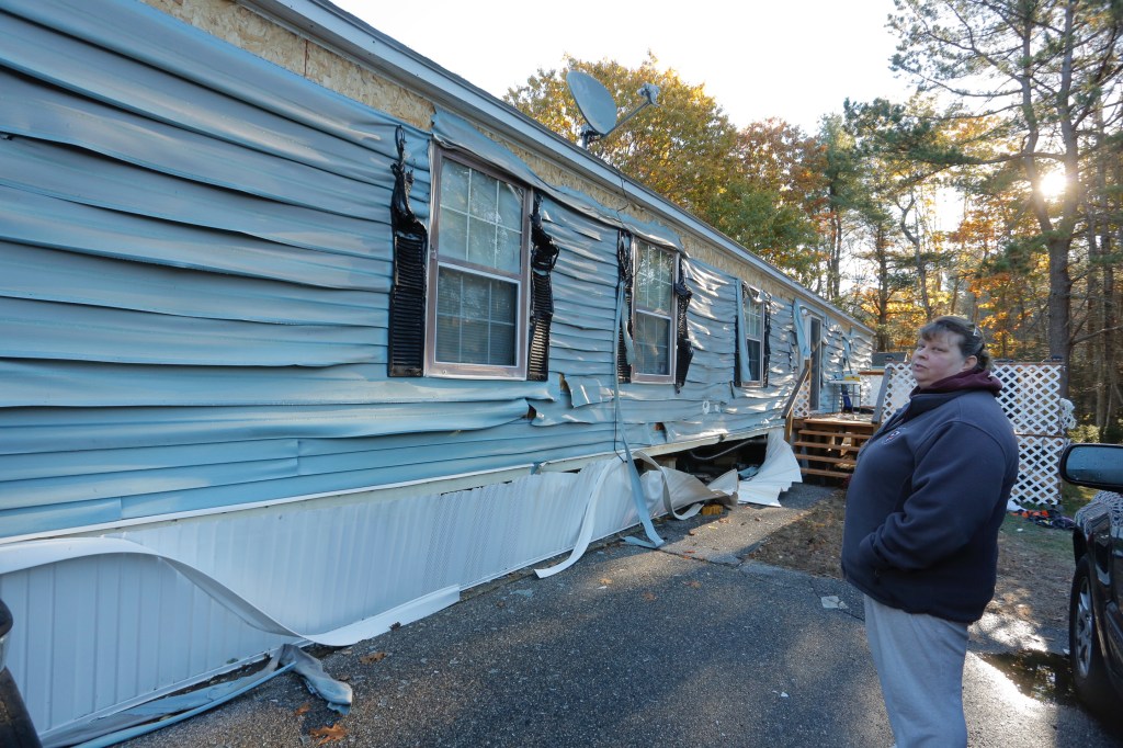 Kim Leclair looks at the melted vinyl siding on her trailer home on Pheasant Road in Saco on Tuesday morning. She and her husband, Bob, live next to the trailer home that exploded at 1:30 a.m. The heat from the fire melted the siding, but firefighters prevented the fire from spreading.