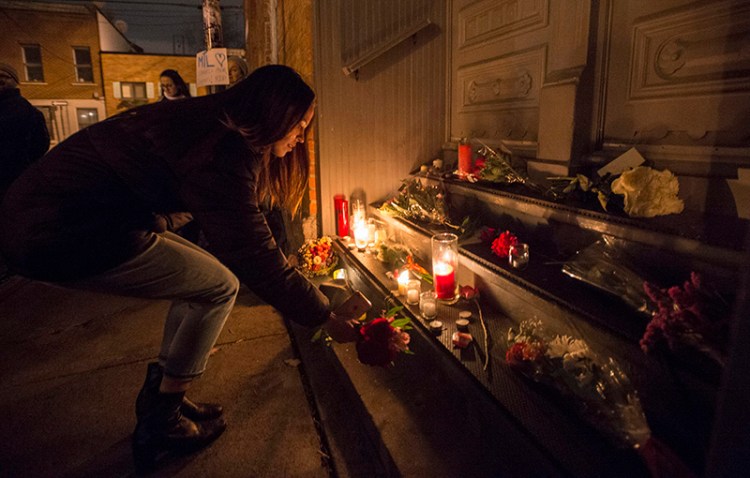 A woman places a candle in front of the home of singer and poet Leonard Cohen in Montreal Thursday evening.