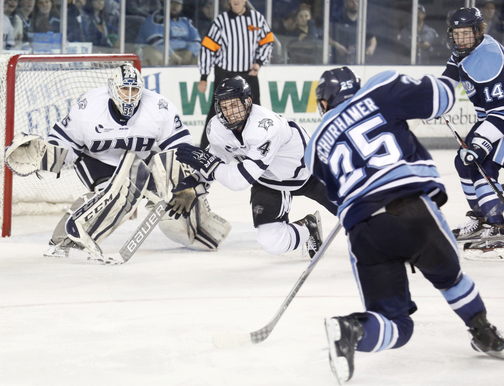 Eric Schurhamer of Maine unleashes a shot in the third period Friday night as Dylan Maller of New Hampshire looks to block it in front of goalie Danny Tirone. New Hampshire scored two goals in the second period and three in the third for a 5-1 victory at home.