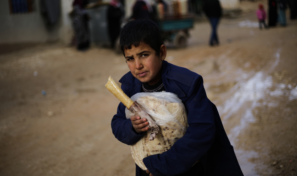 A displaced Syrian boy holds a sandwich and bread bag in the village of Jibreen, south of Aleppo, Syria, on Saturday. Aid agencies say that more than 30,000 people have fled rebel-held eastern neighborhoods of Aleppo.