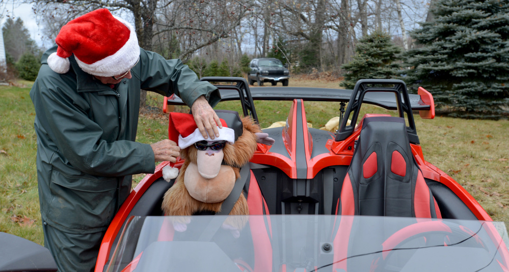 Bryant LaPlante places a Santa Claus hat on his stuffed orangutan, named Harry, on Saturday at The Forest, his Christmas tree farm in Cornville.