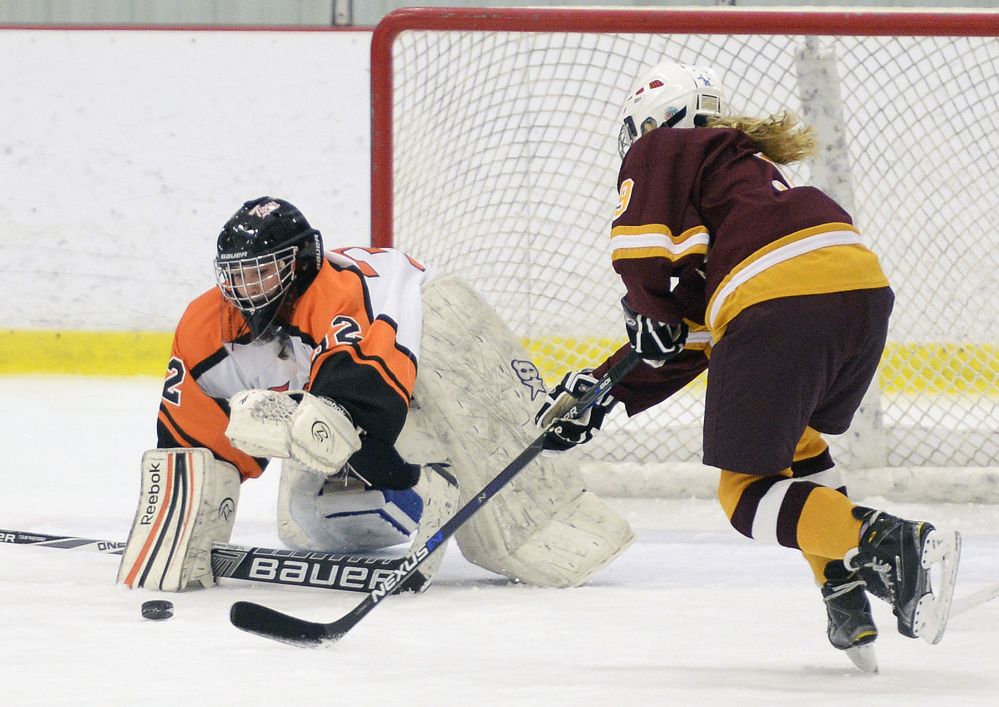 Biddeford/Thornton Academy goalie Bekah Guay dives for the puck as Sophie Miller of Cape Elizabeth/Waynflete/South Portland moves in during a girls' hockey game Saturday afternoon at Biddeford Ice Arena. Cape Elizabeth/Waynflete/South Portland won in overtime, 1-0.