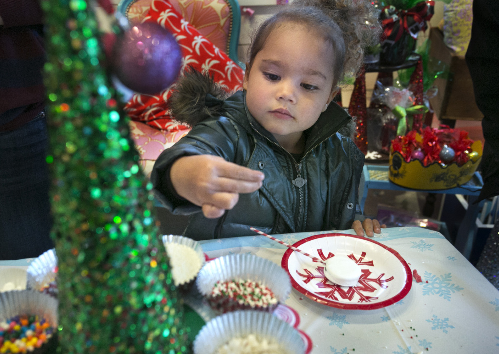 Zola Court-Dickerson, 3, picks out a new topping for an Oreo lollipop dipped in white chocolate that she was decorating during Christmas Prelude in Kennebunk on Saturday.
Gregory Rec/Staff Photographer