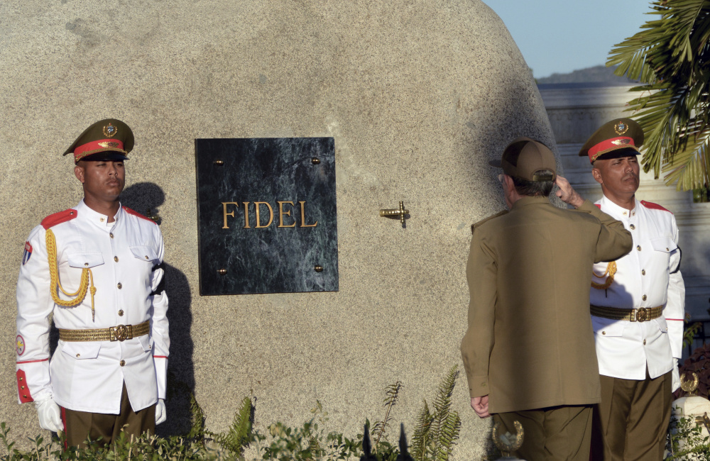 Cuba's President Raul Castro salutes at the tomb of his older brother Fidel, a simple round stone about 15 feet high.