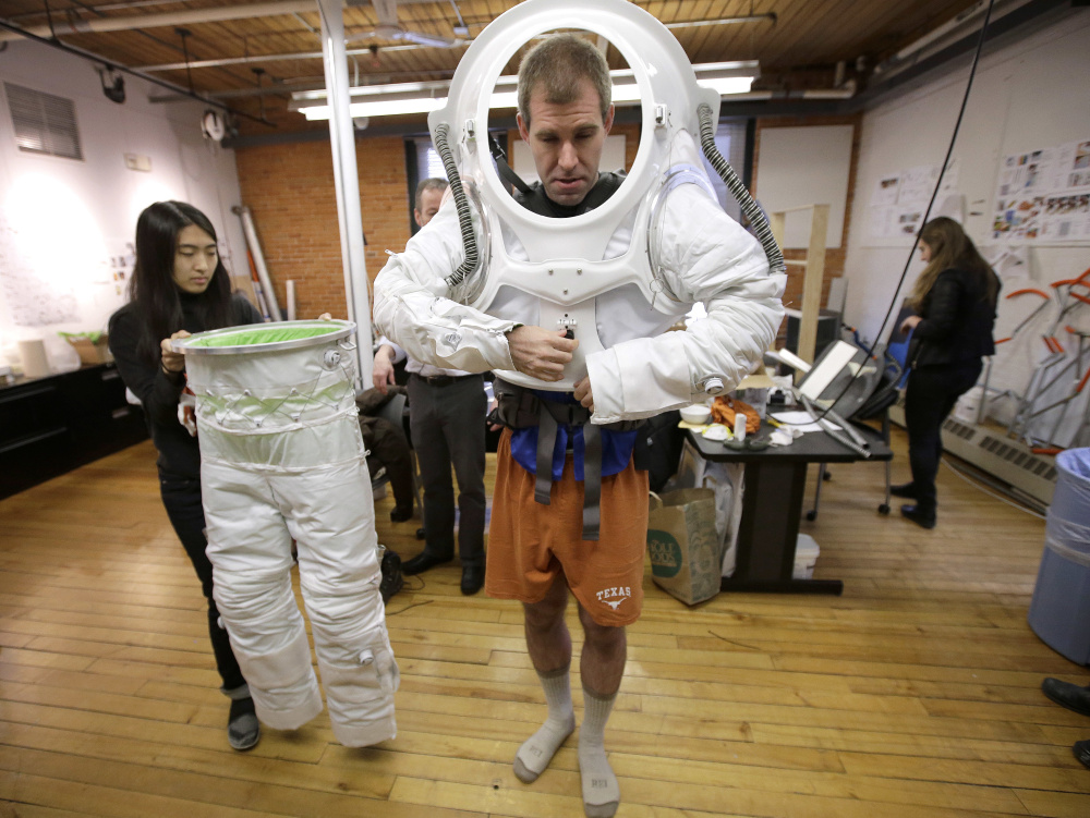 Erica Kim, left, an industrial and apparel design student at the Rhode Island School of Design, helps Andrzej Stewart, the chief engineering officer on a year-long Mars simulation mission that ended in August, put on a new space suit designed by the school.