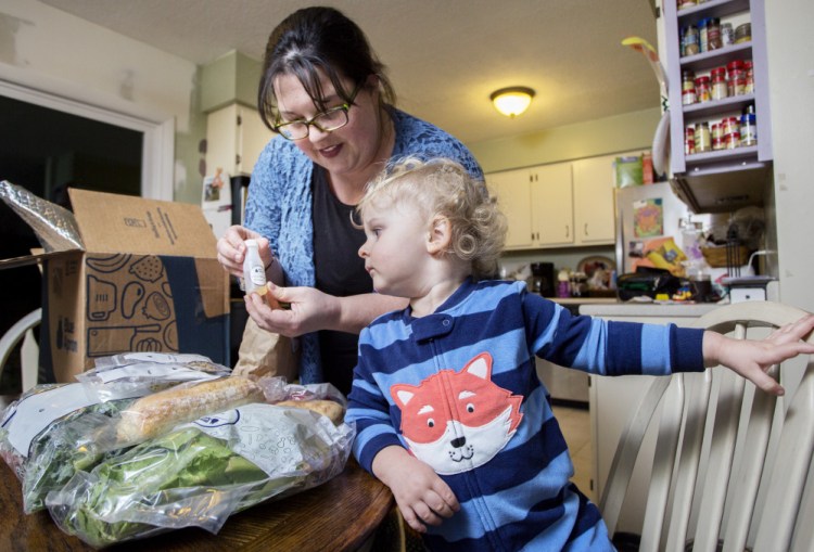 Emily Griffin of Lisbon Falls unpacks a Blue Apron meal kit as her 2-year-old son, Everett, watches. She uses the delivery service for "the convenience factor," she said. Below, the recipe and ingredients for Smoked Trout Tartines.