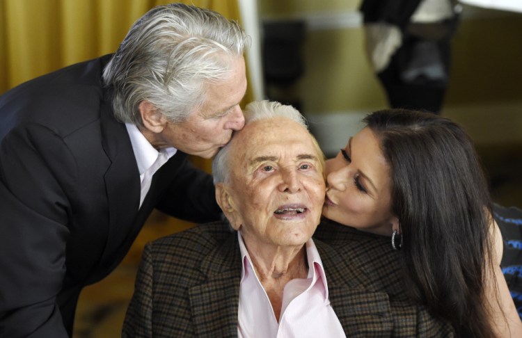 Actor Kirk Douglas, center, gets a kiss from his son Michael Douglas, left, and Michael's wife, Catherine Zeta-Jones, during his 100th birthday party at the Beverly Hills Hotel on Friday in Beverly Hills, Calif.