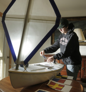 Seven classmates in Kennebunk High School's Alternative Education program joined with a land trust and The Landing School to build a 5-foot boat that will depart from coastal Maine and steer itself across the Atlantic. Senior David Patoine, above, puts a sticker on the boat, which will be launched about 150 miles offshore.
