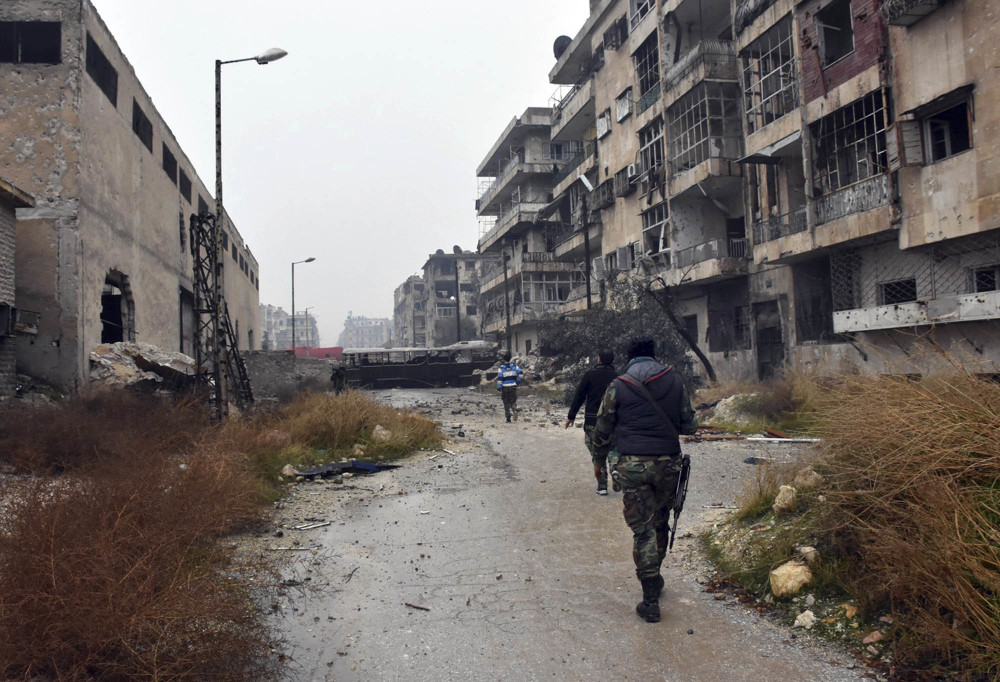Syrian troops and pro-government gunmen march through the streets of east Aleppo, Syria, on Tuesday.