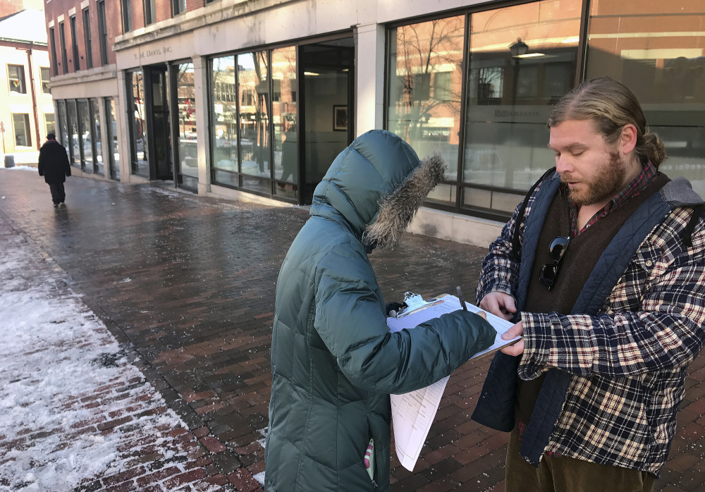 A woman signs a petition to put Medicare expansion on the Maine ballot in 2016. George Frangoulis, of Portland, working for the Maine People's Alliance, was gathering signatures in Monument Square in Portland.
