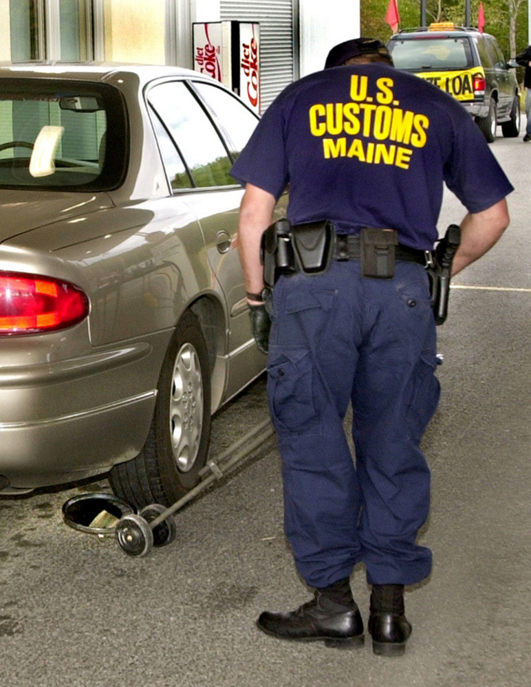 A U.S. Customs official uses a special mirror and light device to check under a car being inspected at the Jackman border crossing in 2001. A new bill would require the federal Department of Homeland Security to evaluate security threats at the northern border.