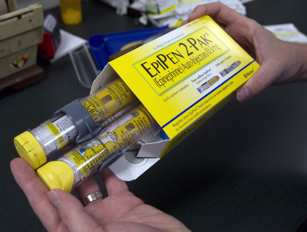 A pharmacist holds a package of EpiPens in Sacramento, Calif.  Mylan has started selling a generic version of its emergency allergy treatment at half the price of the branded option.