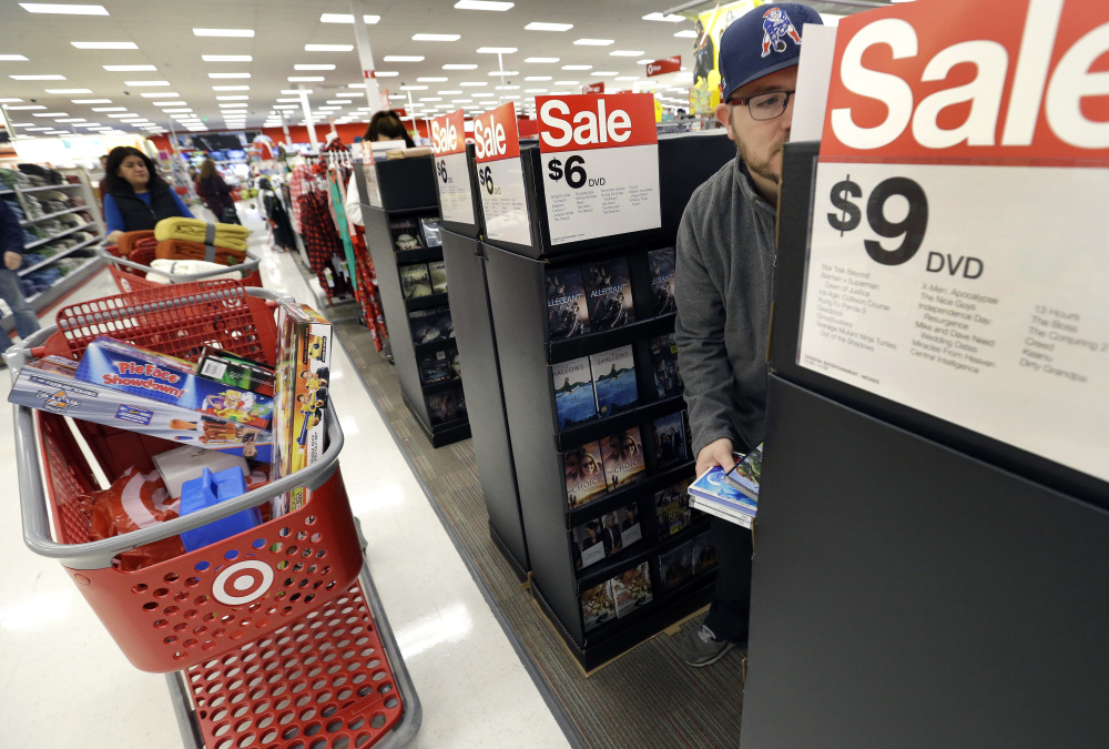 Paul Poirier shops for sales at a Target, in Wilmington, Mass. Retailers are pushing promotions and other enticements for the final stretch of the holiday season as new sales numbers show shoppers are spending at a decent rate, but are a tad slower compared to the last holiday season.