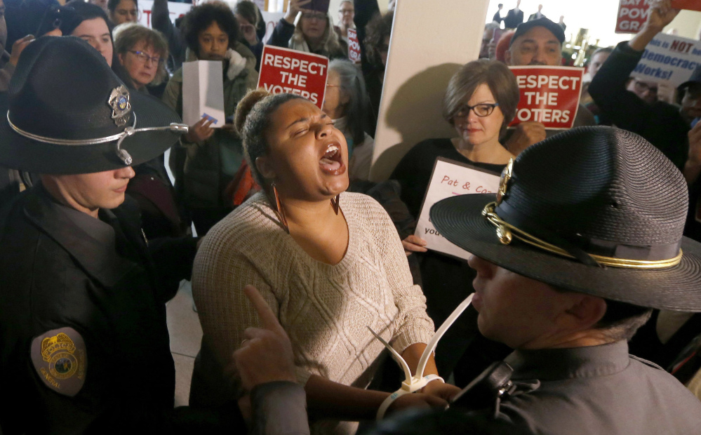 A protester is one of more than 50 arrested outside the House gallery during a special session of the North Carolina General Assembly in Raleigh on Friday.
