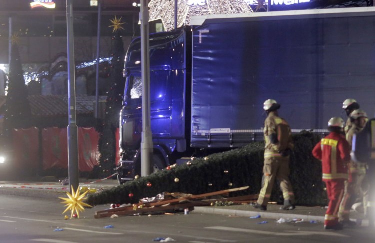 Firefighters stand beside the truck that ran into a crowd in Berlin. 
