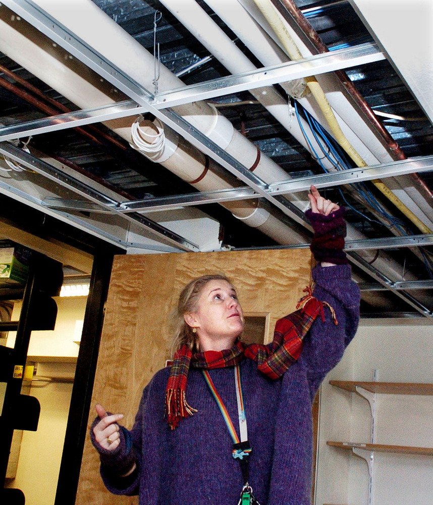 At left, Waterville Public Library Director Sarah Sugden identifies the pipe that burst, drenching about 50 nonfiction children's books. Above, CDs, audiobooks and cases are spread out to dry Monday at the library. Carpeting in two rooms, ceiling tiles, walls and the lobby floor were also damaged.