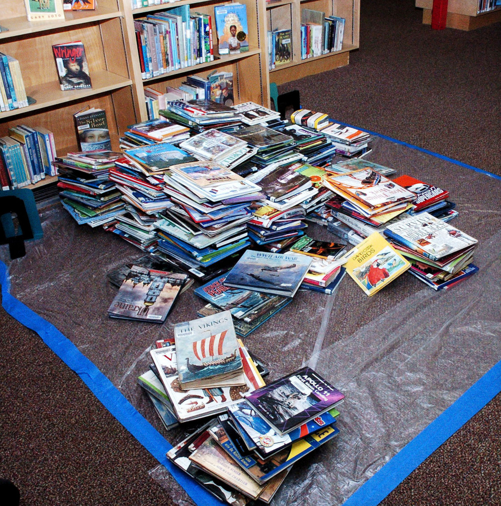Children's books lay on a tarp at the Waterville Public Library on Monday after a water pipe broke and flooded the library building and damaged books over the weekend.