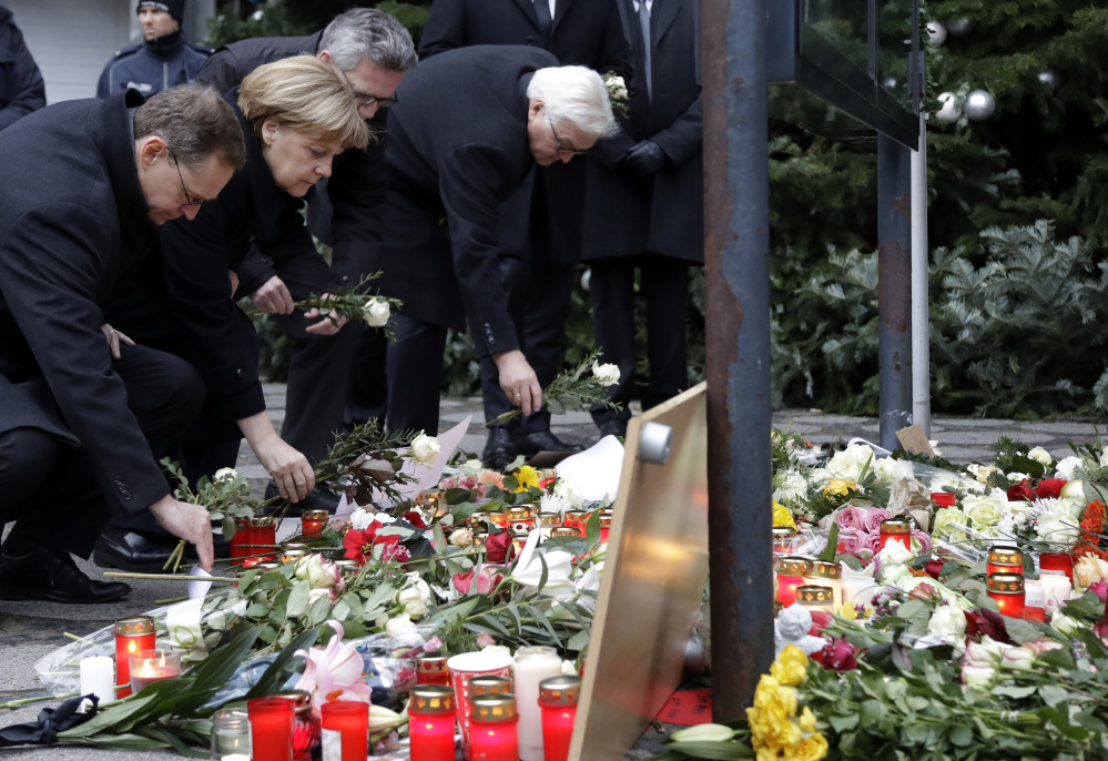From left, Berlin Mayor Michael Mueller, Chancellor Angela Merkel, Interior Minister Thomas de Maiziere and Foreign Minister Frank-Walter Steinmeier attend a flower ceremony at the Kaiser-Wilhelm-Gedaechniskirche in Berlin on Tuesday, the day after a truck ran into a crowded Christmas market and killed 12 people.