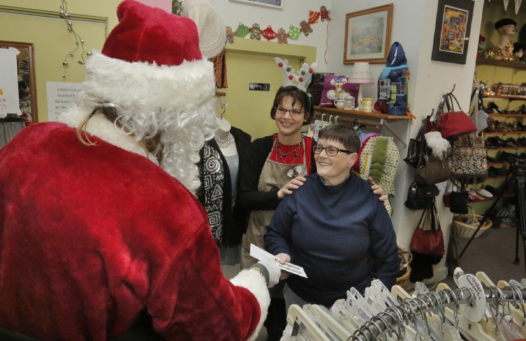 Secret Santa hands out envelopes containing $100 bills at the Still a Good Cause Thrift Shop in Portland on Tuesday. The anonymous donor plans to hand out $20,000 this year, bringing his total donations over the past eight years to $160,000.