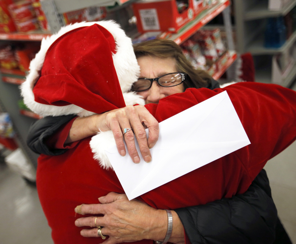 Germaine Norbert of Springvale hugs Secret Santa Maine after receiving an envelope with $100 while shopping at Family Dollar in Sanford.