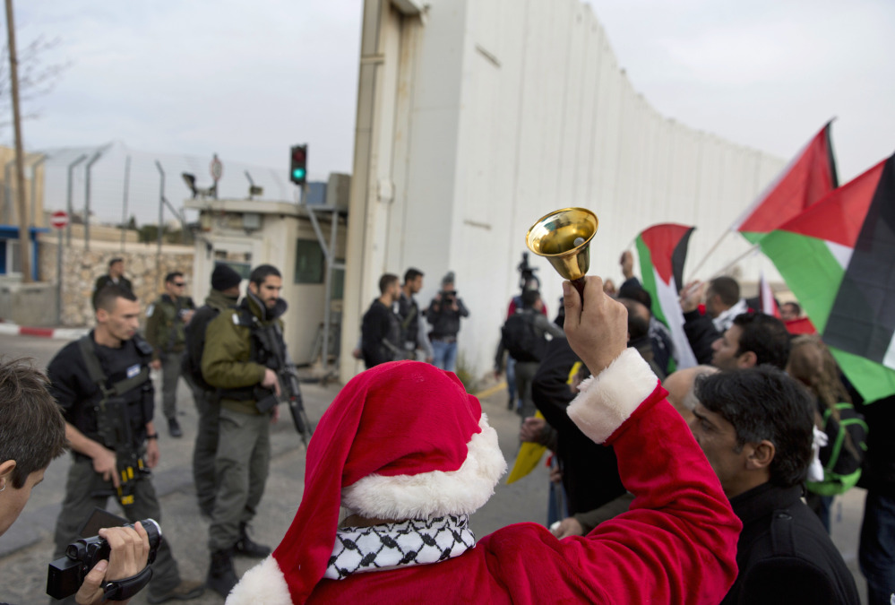 Palestinian protesters, some dressed as Santa Claus, carry Palestinian flags and chant anti Israel slogans during a protest in front of an Israeli checkpoint, in the West Bank city of Bethlehem, Friday. In a Christmas greeting on Friday, Palestinian President Mahmoud Abbas said: "Despite the Israeli occupation, our presence in our homeland and the preservation of our cultural and national heritage are the most important form of resistance in the face of the darkness of a foreign colonialist occupying power."