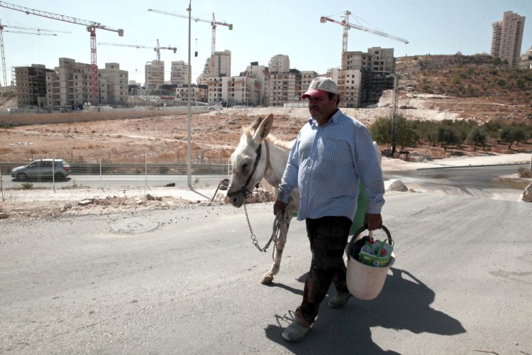 A Palestinian man walks near a construction site of a new housing unit in the east Jerusalem neighborhood of Har Homa. The U.N. Security Council on Friday condemned Israel's settlements and continuing construction in Palestinian territory as a 'flagrant violation' of international law.