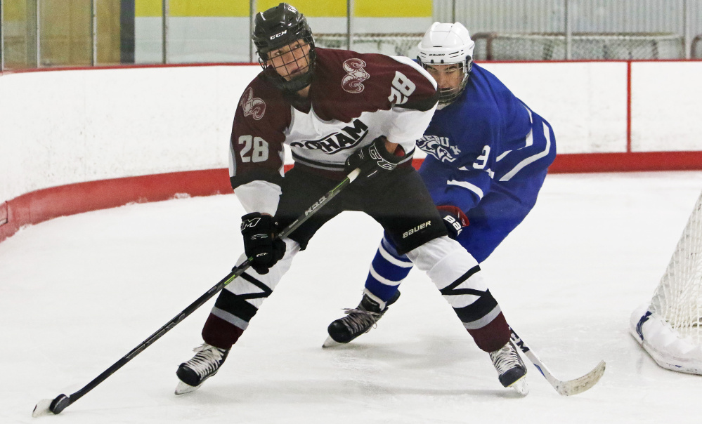Trevor Gray of Gorham handles the puck behind the net while being pursued by Jakub Simikak of Kennebunk during the second period.