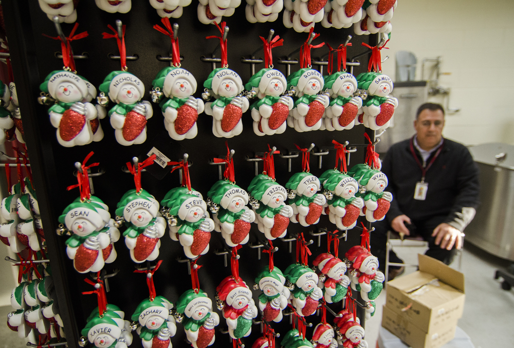Fitchburg High School athletic director Ray Cosenza sits beside ornaments recently donated by Ornament Central to Fitchburg Public Schools for a fundraiser for the athletic department. Officials at Ornament Central, a family-owned wholesaler, said they will move 600,000 ornaments resulting in more than $1.6 million in sales.