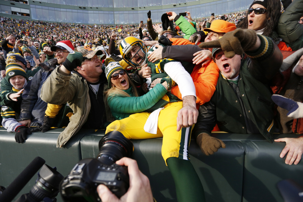 Packers quarterback Aaron Rodgers celebrates his touchdown run with fans during Saturday's game against the Minnesota Vikings. Green Bay stayed in playoff position with its fifth straight win – 38-25.