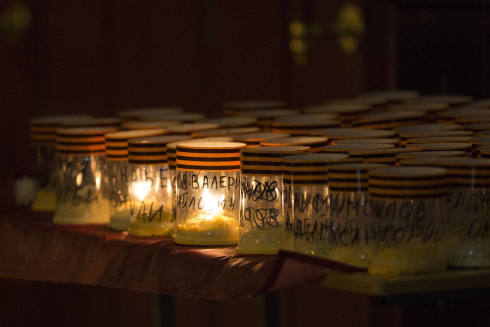 The names of  the victims of a military choir and St. George's ribbons are placed on candles, in front of the Alexandrov Ensemble building in Moscow, Russia, Monday, the day after a plane carrying 64 members of the Alexandrov Ensemble crashed into the Black Sea minutes after taking off from the resort city of Sochi.