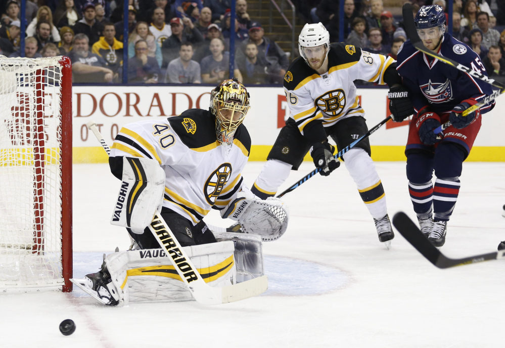 Bruins goalie Tuukka Rask makes a save as teammate Kevan Miller and the Blue Jackets' Lukas Sedlak look for the rebound during the second period of Tuesday night's game in Columbus, Ohio.
