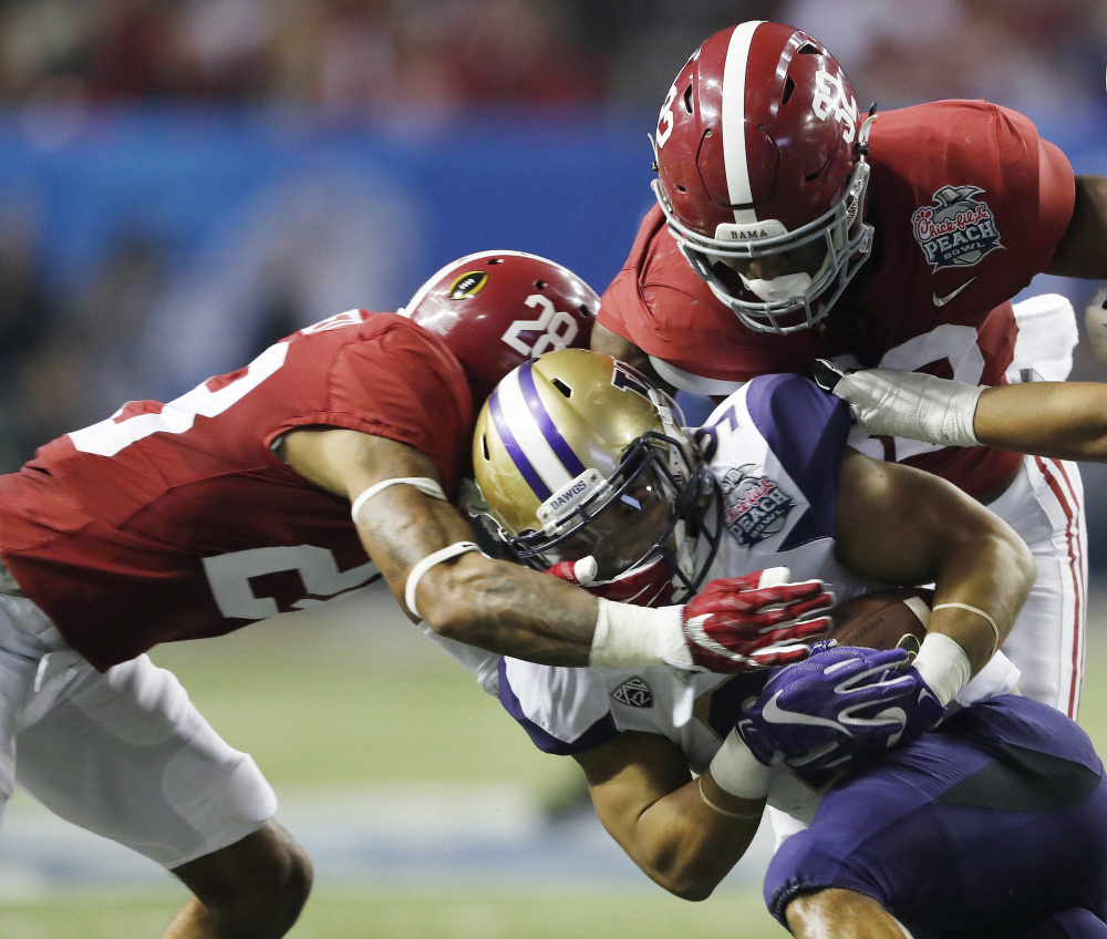 Washington running back Myles Gaskin is stopped by Alabama defensive back Anthony Averett, left, and linebacker Rashaan Evans during the second half of the Peach Bowl on Saturday in Atlanta. Alabama won 24-7 and advanced to the national championship game on Jan. 9. (Associated Press/John Bazemore)
