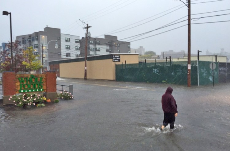 A pedestrian wades from the Whole Foods Market parking lot across Pearl Street in Portland's Bayside neighborhood during heavy rains on  Sept. 30, 2015. <em>Gabe Souza/Staff Photographer</em>