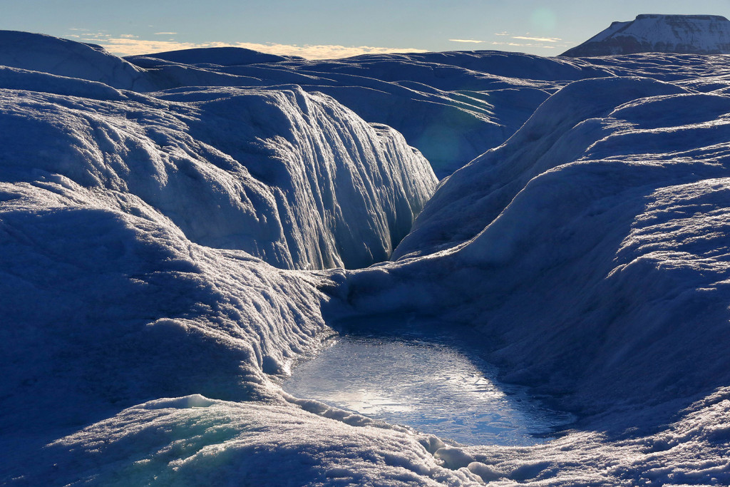 A pool of frozen water rests on the bumpy, often wet surface of Petermann Glacier.