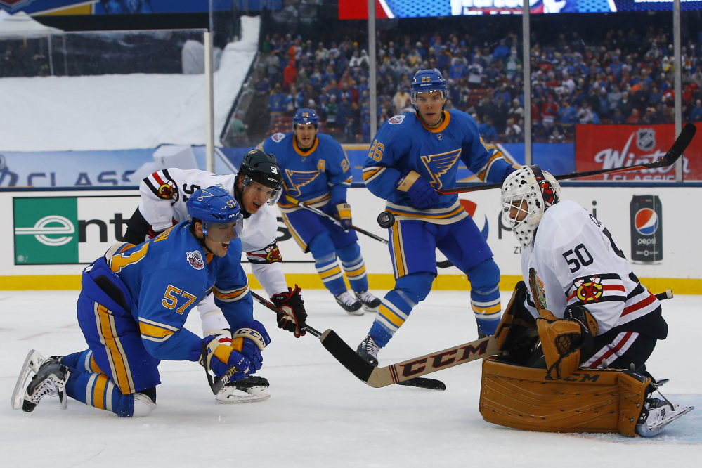 St. Louis Blues' David Perron, left front, is checked to the ice by Chicago Blackhawks' Brian Campbell, second from left, after taking a shot against Blackhawks goalie Corey Crawford, right, during the second period of the NHL Winter Classic on Monday at Busch Stadium in St. Louis.
