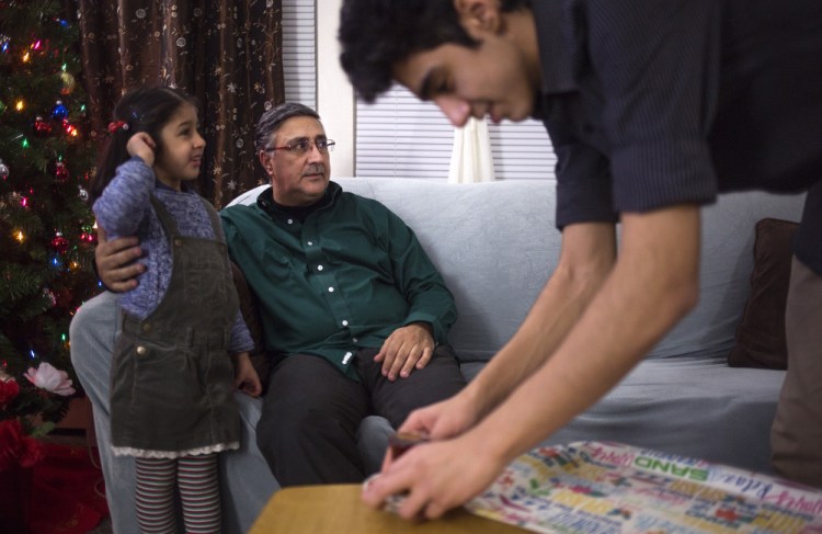 Abdullah Ali, 16, serves tea to his father, Ahmed Ali, seated with his daughter Fatimas, 6, at their apartment in Westbrook. After police met with residents about anti-Muslim messages left at the complex, many of his neighbors and friends felt reassured, Ali said.