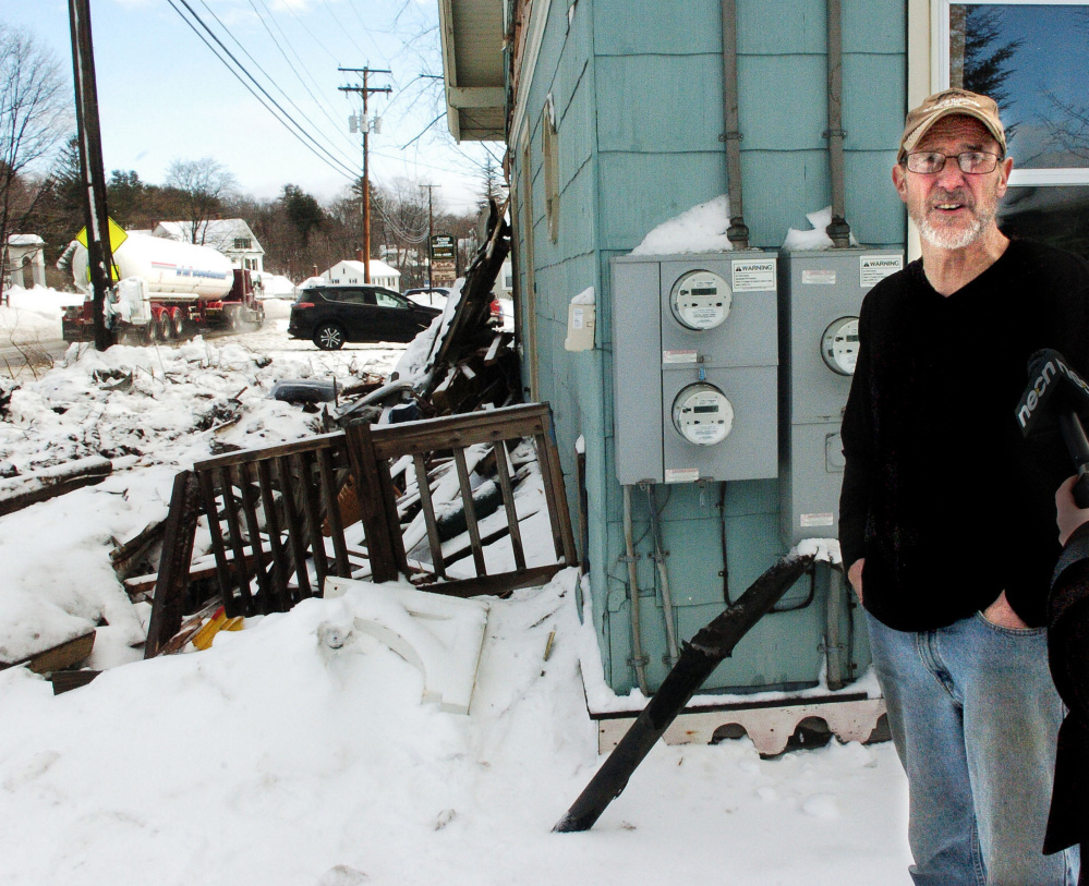 As a truck passes Wednesday, Richard Faeth talks about the truck accident Tuesday night that destroyed the porch in front of his home on Fairbanks Road in Farmington.