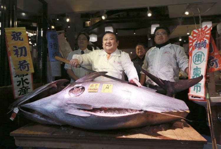 Kiyoshi Kimura, center, president of Kiyomura Co., poses with the 466-pound bluefin tuna he bought for $632,000 at the annual New Year auction, at his Sushi Zanmai restaurant near Tsukiji fish market in Tokyo on Thursday.