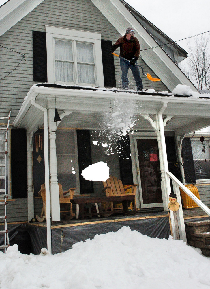 David Austin removes snow this week from the roof of a friend's home in the central Maine town of Fairfield.