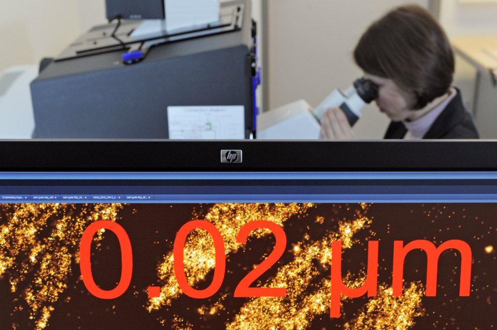Almut Horch works with a microscope system behind a monitor where cancer cells are visualized in Jena, Germany.