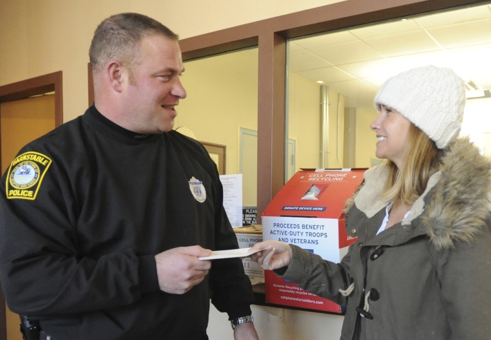 Recovery Without Walls volunteer Lisa Kelliher gives Barnstable police officer Mark McWilliams a gift card to Dunkin' Donuts as a thank you for serving the at-risk.