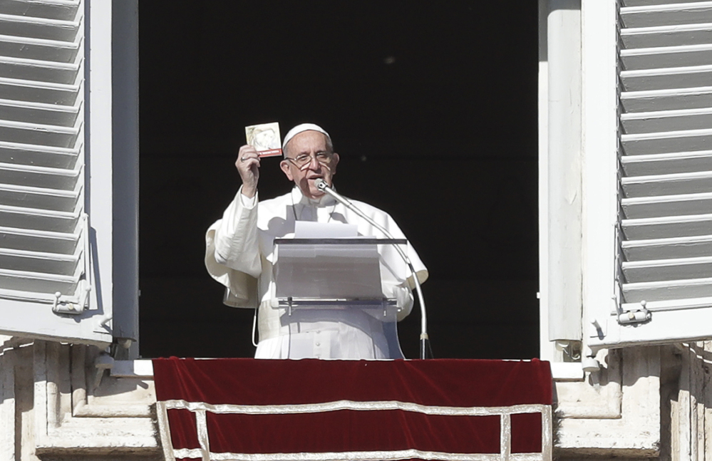 Pope Francis shows a booklet on Jesus Christ that will be distributed to faithful during the angelus prayer from his studio's window overlooking St. Peter's square, at the Vatican, Friday, Jan. 6, 2017. (AP Photo/Andrew Medichini)