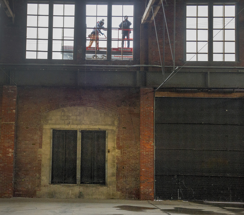 Workmen repair windows in the large warehouse.
