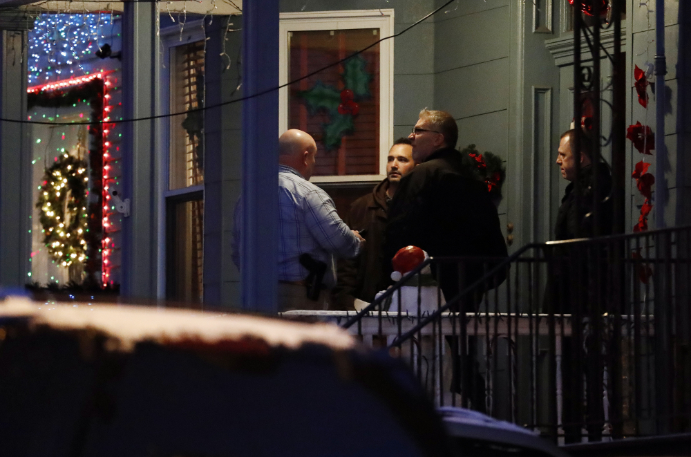 Officials are seen speaking to people believed to be family members of Esteban Santiago at a home in Union City, N.J., on Friday. Santiago is suspected of being the gunman in the shooting at the Fort Lauderdale-Hollywood International Airport.