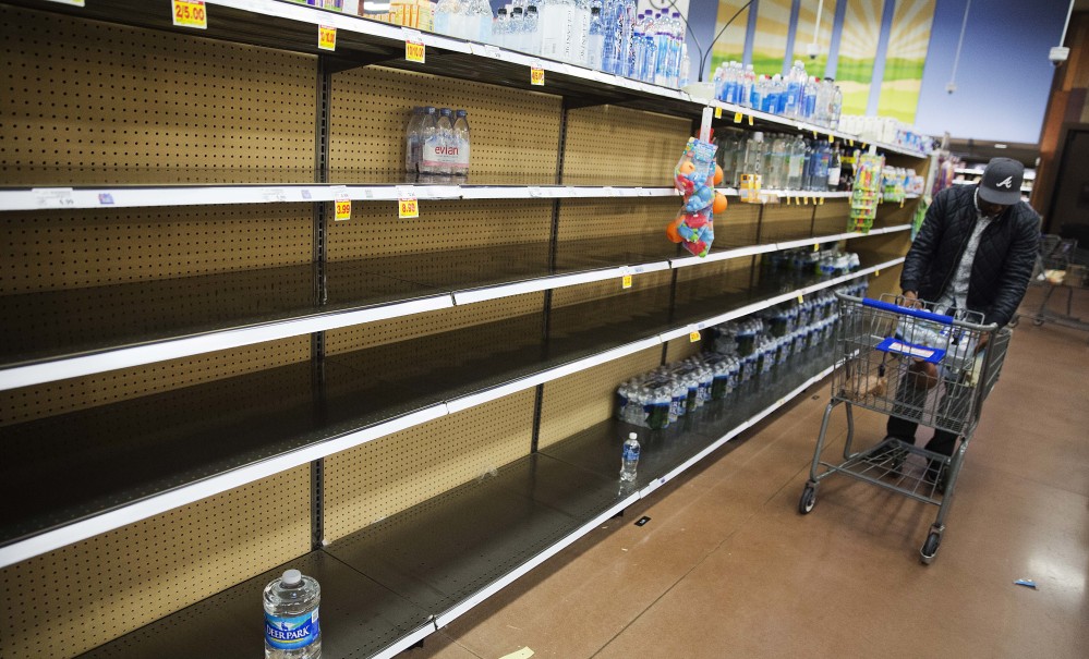Shelves of bottled water sit mostly empty at a supermarket in Atlanta on Friday. Shoppers emptied shelves of bread and milk, road workers began working 12-hour shifts, and states of emergency were declared in Alabama, Georgia and the Carolinas ahead of a winter storm stalking the South.
