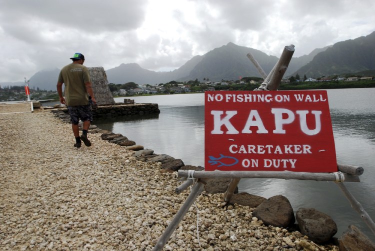 Conservation International's Luka Mossman, who restores and researches Native Hawaiian fishponds, walks along a barrier wall on Heeia fishpond in Kaneohe, Hawaii. U.S. officials are working on a plan to expand fish farming into federal waters around the Pacific Ocean. 