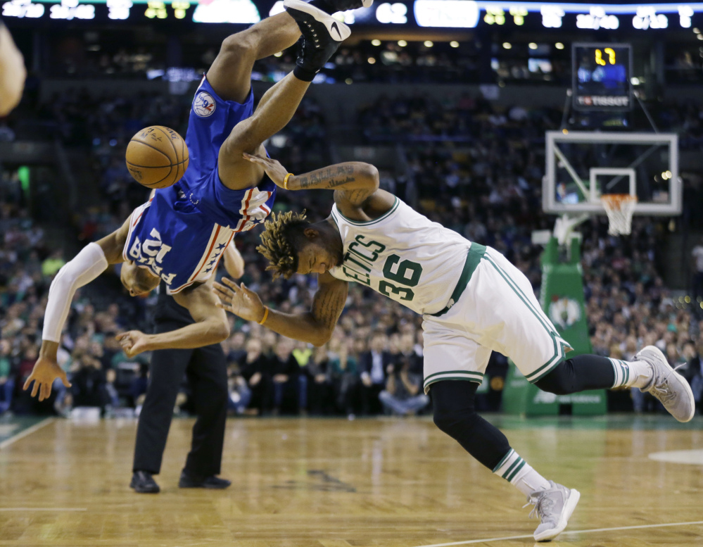 Philadelphia guard Gerald Henderson falls as he tries to block a shot by Boston's guard Marcus Smart in the second quarter Friday night in Boston.