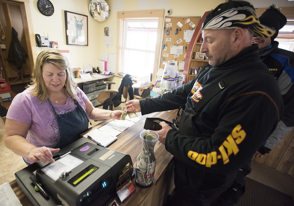 Proprietor Terry Hill waits on snowmobilers as they gas up their machines and eat at her family's restaurant at Shin Pond Village in the Penobscot County town of Mount Chase last week. Hill was originally opposed to the creation of the Katahdin Woods and Waters National Monument, but has come to embrace its positive effects on business.